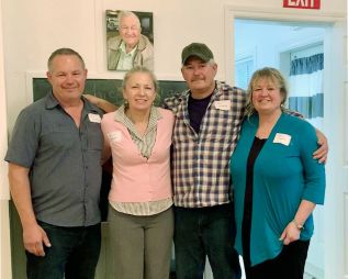 The Meeks family gathered at the schoolhouse under Archie’s photograph .